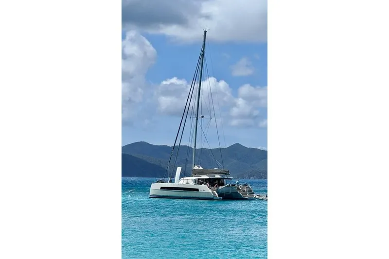 Slide: The Image of 2021 Catana 53 catamaran sailing in turquoise waters with mountainous backdrop. - 11