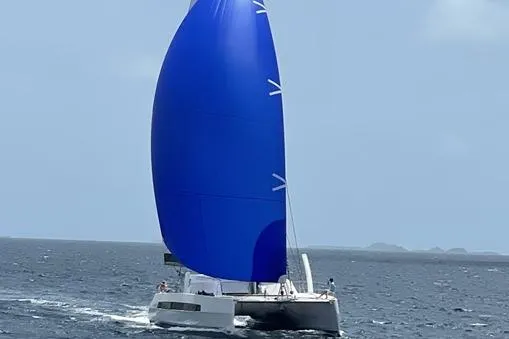 Slide: The Image of 2021 Catana 53 sailing catamaran with a large blue sail on open water. - 13