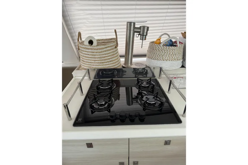 Slide: The Image of Modern kitchen stove on Catana 53 yacht, 2021 model, with sleek black cooktop and baskets. - 50