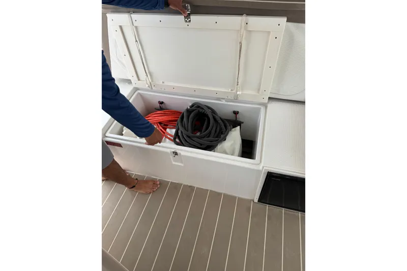 Slide: The Image of Open storage compartment on 2021 Catana 53 yacht with coiled hoses inside. - 76