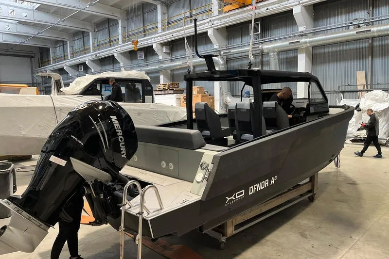 The Image of 2026 XO DFNDR A8 boat in a warehouse with Mercury engine. - 1