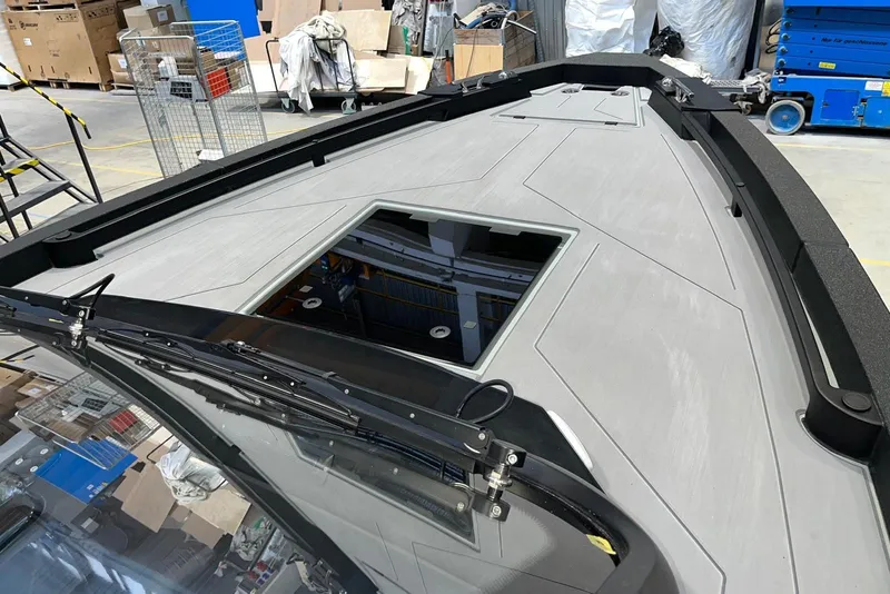 Slide: The Image of 2026 XO DFNDR A8 boat deck with open hatch in a workshop setting. - 25