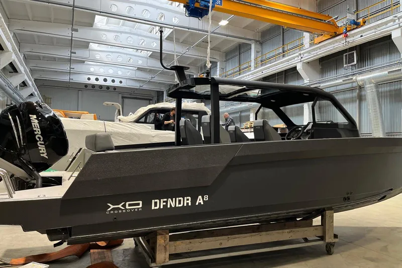 Slide: The Image of 2026 XO DFNDR A8 boat in a warehouse, featuring a sleek design and Mercury engine. - 40