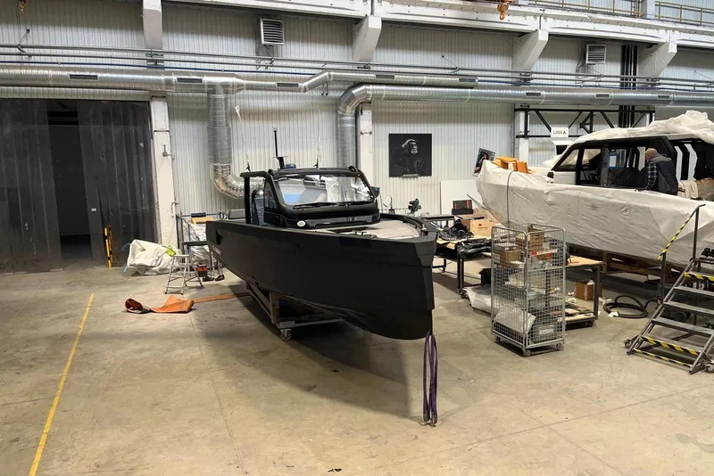 Slide: The Image of 2026 XO DFNDR A8 boat in a workshop, under construction with tools and equipment nearby. - 5