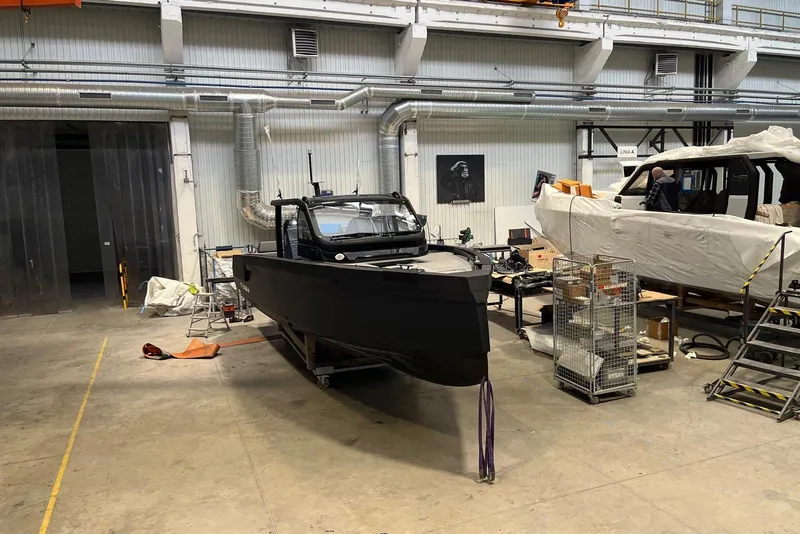 Slide: The Image of 2026 XO DFNDR A8 boat in a workshop, surrounded by tools and equipment. - 6