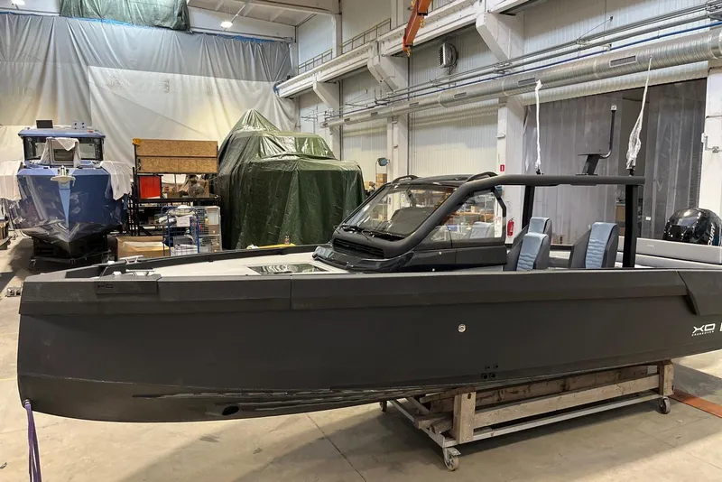Slide: The Image of 2026 XO DFNDR A8 boat in a workshop, surrounded by other vessels and equipment. - 8