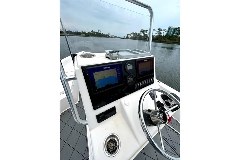 Slide: The Image of 2004 Pathfinder 2200 V boat console with navigation screens and steering wheel on a calm waterway. - 5