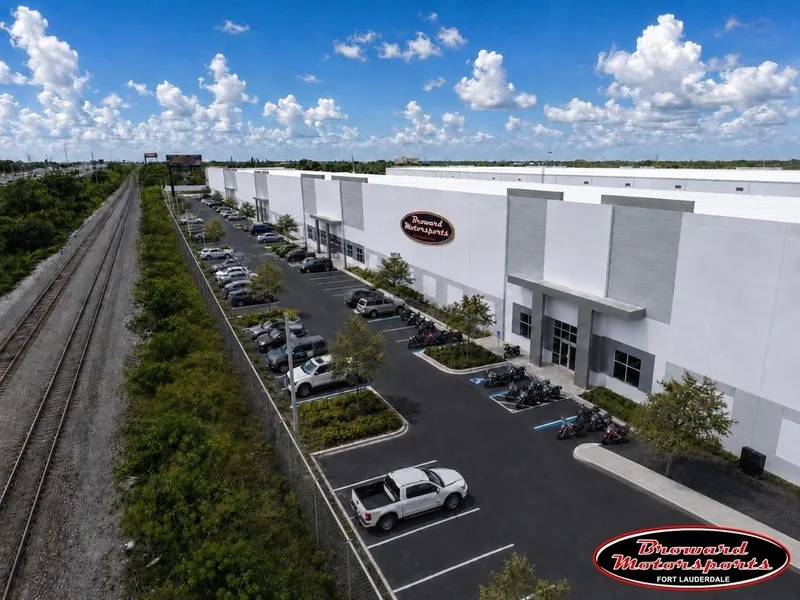Slide: The Image of A modern building with a parking lot full of cars and motorcycles, next to a railway line. - 8