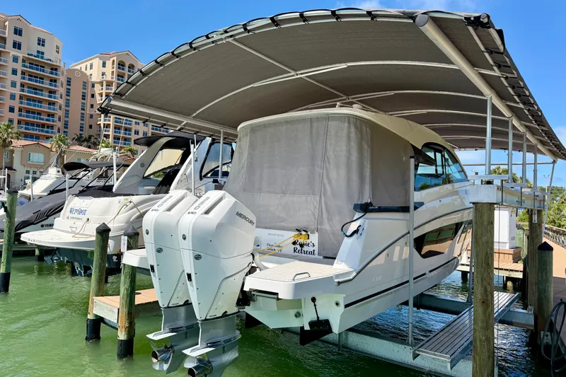 Slide: The Image of 2024 Beneteau Gran Turismo 32 yacht docked under canopy, featuring twin Mercury engines. - 14