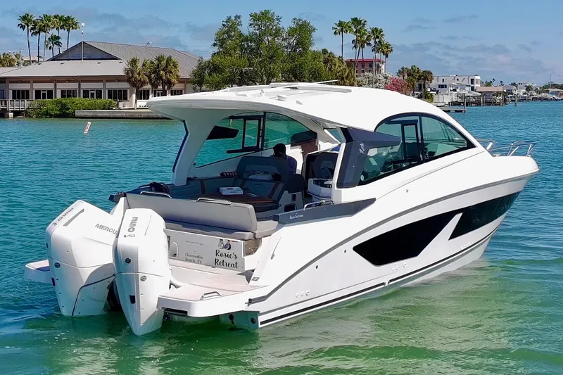 Slide: The Image of 2024 Beneteau Gran Turismo 32 yacht cruising on clear blue water near a coastal town. - 38