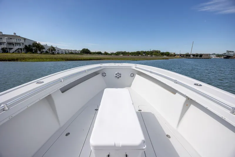 Slide: The Image of 2002 Yellowfin 31 Center Console boat on calm water, clear sky, residential backdrop. - 21