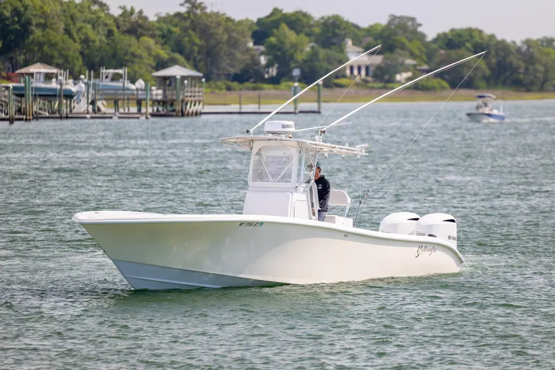 Slide: The Image of 2002 Yellowfin 31 Center Console boat cruising on a calm lake near docks. - 4