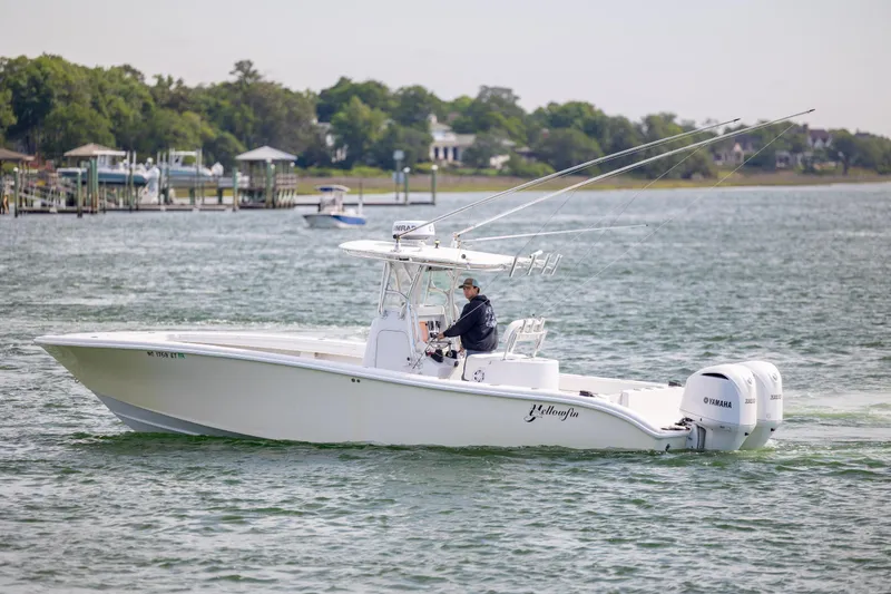 Slide: The Image of 2002 Yellowfin 31 Center Console boat cruising on a calm lake with a driver. - 6