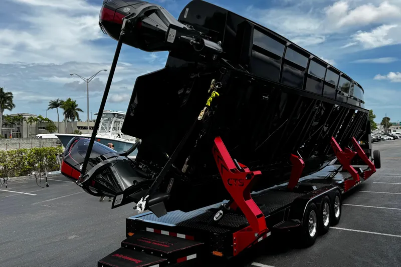 Slide: The Image of 2025 Performance Powerboats P420 on trailer, sleek black design, parked under blue sky. - 35