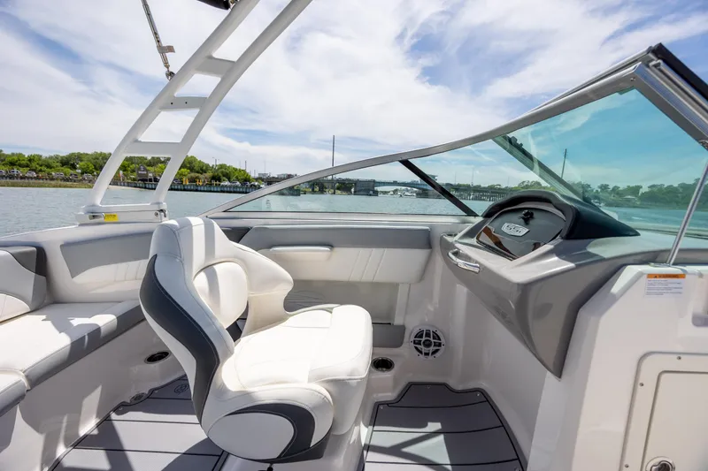 Slide: The Image of 2023 Chaparral 21 SSi boat interior with helm and seating, on a sunny day. - 13