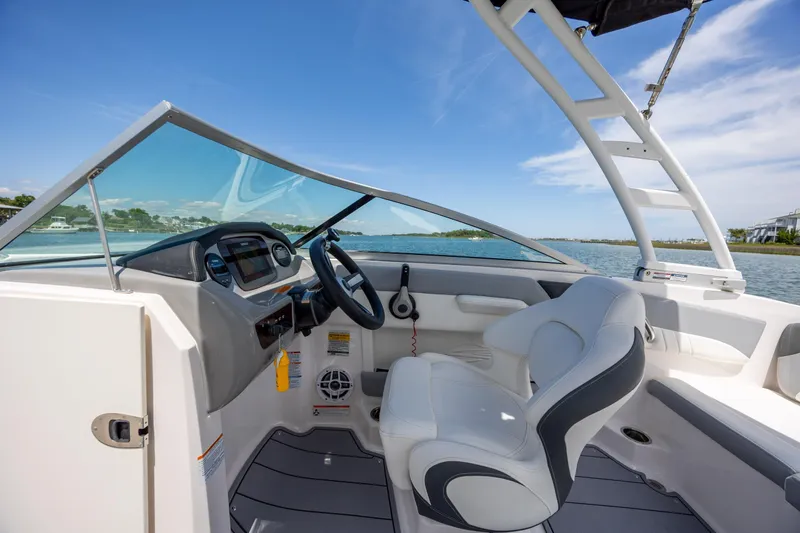 Slide: The Image of 2023 Chaparral 21 SSi boat interior with steering wheel and seating, on a sunny day. - 15