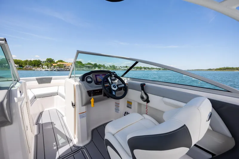 Slide: The Image of 2023 Chaparral 21 SSi boat interior with steering wheel, dashboard, and seating on a sunny day. - 18