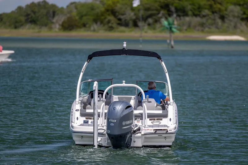 Slide: The Image of 2023 Chaparral 21 SSi boat cruising on a serene lake with lush greenery. - 4