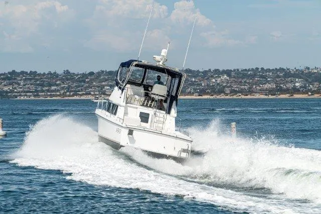 Slide: The Image of 2011 Skipjack 300 Flybridge cruising on open water near a coastal city. - 14