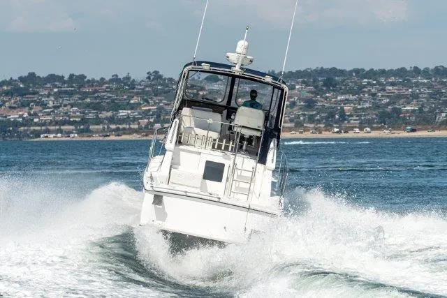 Slide: The Image of Skipjack 300 Flybridge 2011 cruising on open water with coastal cityscape in background. - 15