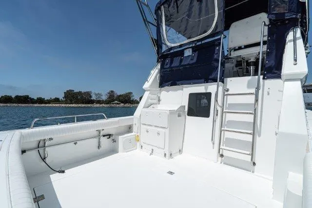 Slide: The Image of 2011 Skipjack 300 Flybridge boat with spacious deck and ladder, docked by the water. - 26
