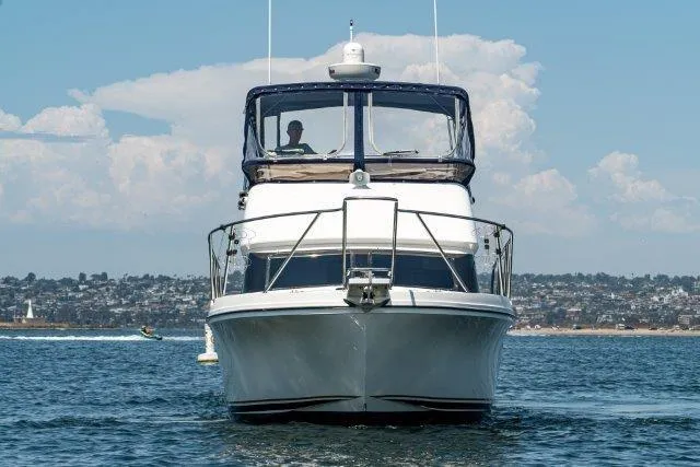 Slide: The Image of 2011 Skipjack 300 Flybridge yacht cruising on open water with scenic coastal backdrop. - 3