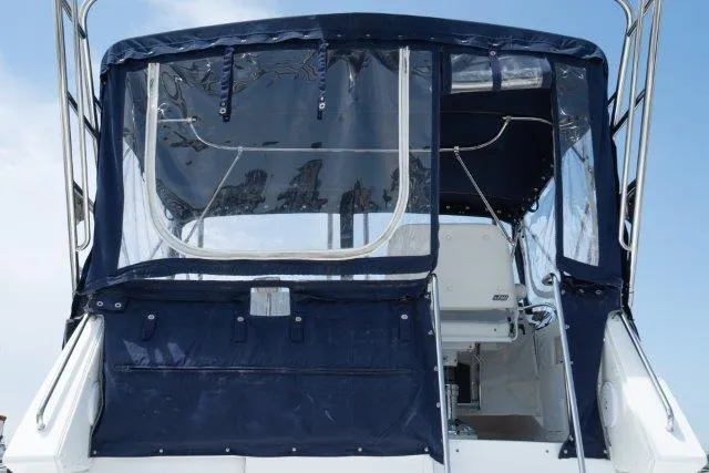 Slide: The Image of 2011 Skipjack 300 Flybridge boat with blue canvas enclosure, rear view. - 47