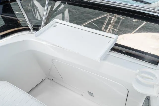 Slide: The Image of 2011 Skipjack 300 Flybridge interior with white seating and table, overlooking water. - 56