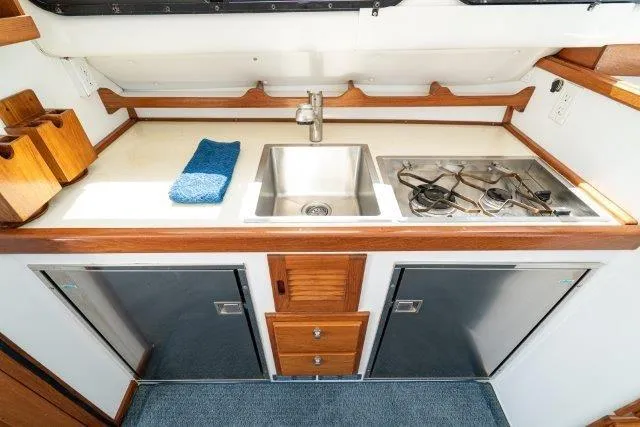 Slide: The Image of 2011 Skipjack 300 Flybridge kitchen with sink, stove, and storage cabinets. - 61