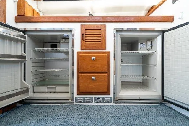 Slide: The Image of Open dual refrigerators and wooden drawers in a 2011 Skipjack 300 Flybridge boat interior. - 62