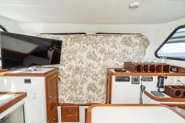 Slide: The Image of Interior of 2011 Skipjack 300 Flybridge with TV, floral curtain, and control panel. - 70