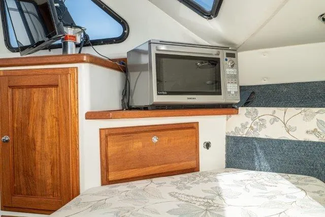 Slide: The Image of Interior of 2011 Skipjack 300 Flybridge with microwave and wooden cabinetry. - 76