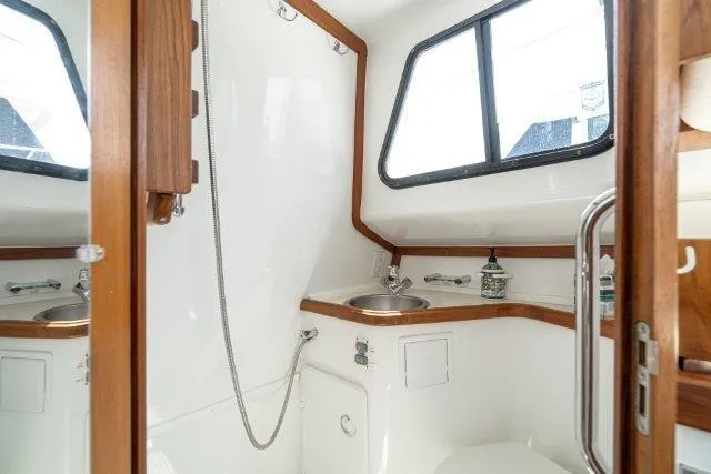 Slide: The Image of 2011 Skipjack 300 Flybridge boat bathroom with sink, shower, and wooden accents. - 77