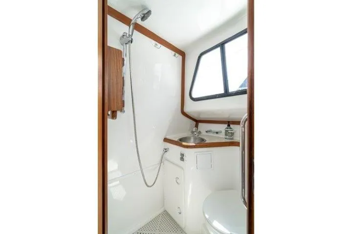 Slide: The Image of 2011 Skipjack 300 Flybridge bathroom with shower, sink, and window, featuring modern design. - 78