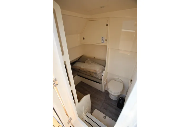 Slide: The Image of Interior cabin of 2022 Scout 330 LXF boat, featuring a compact bed and toilet. - 34