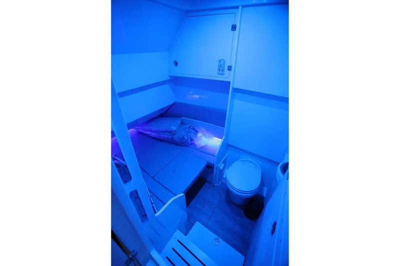 Slide: The Image of 2022 Scout 330 LXF cabin interior with blue lighting, featuring a bed and toilet. - 44