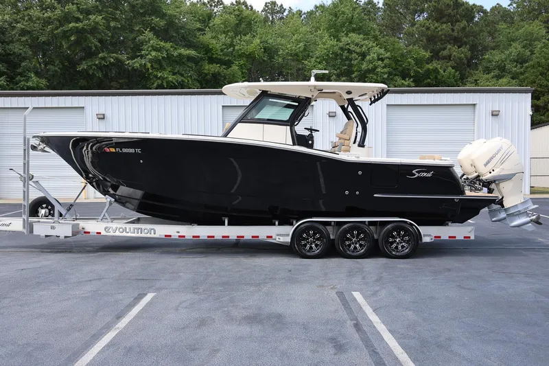 Slide: The Image of 2022 Scout 330 LXF boat on trailer, parked outdoors near storage facility. - 5