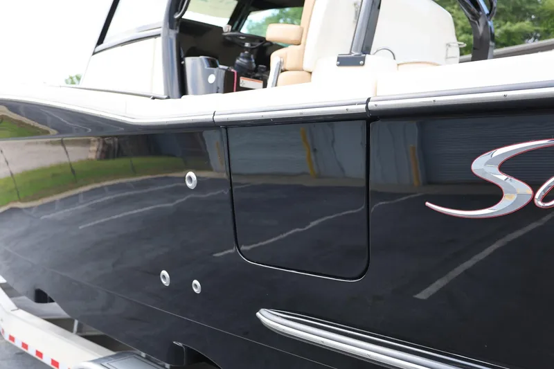 Slide: The Image of 2022 Scout 330 LXF boat, sleek black exterior with logo, parked on a trailer. - 6