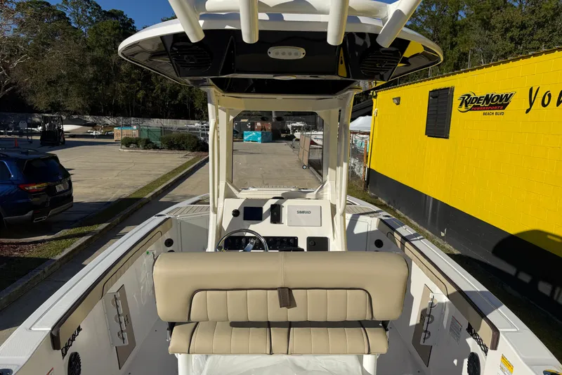 Slide: The Image of 2026 Yamaha Boats 222 FSH Sport E interior, featuring helm and seating, parked outdoors. - 12
