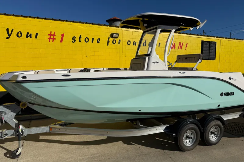 Slide: The Image of 2026 Yamaha Boats 222 FSH Sport E on trailer, yellow wall background. - 2