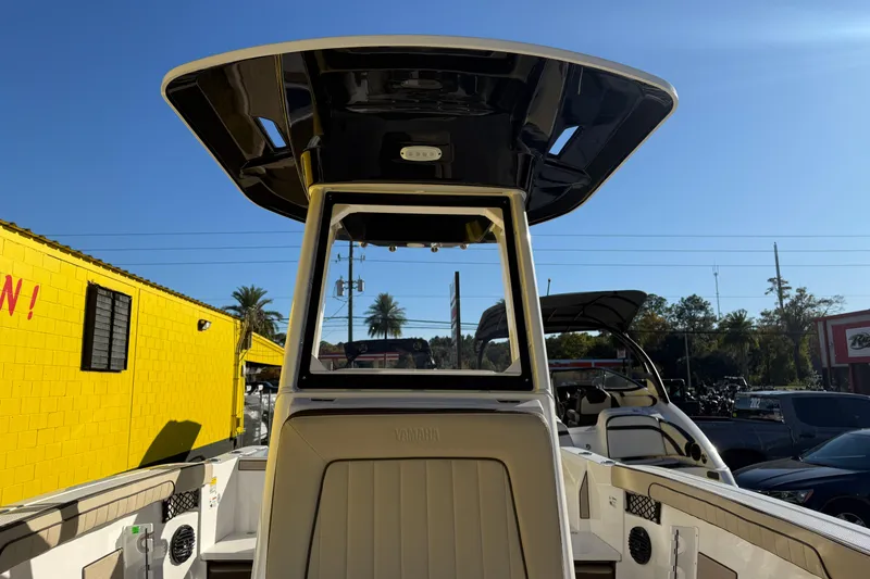 Slide: The Image of 2026 Yamaha Boats 222 FSH Sport E center console with T-top, parked outdoors. - 26