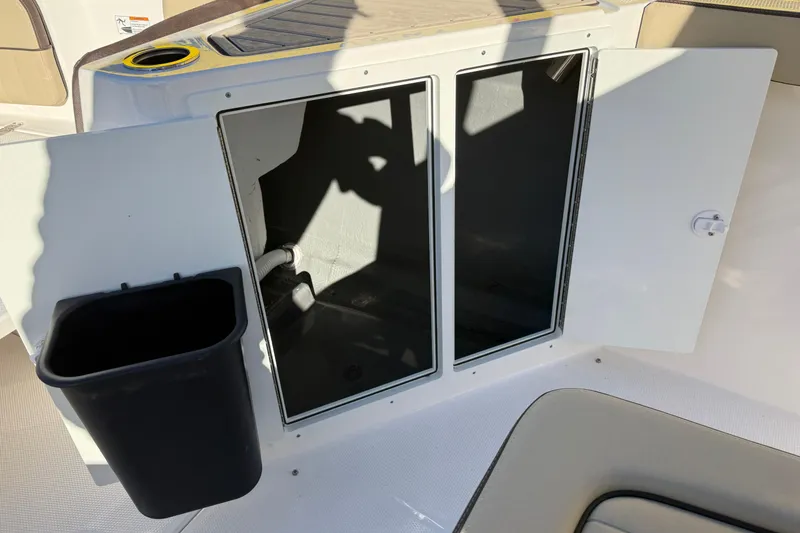 Slide: The Image of Open storage compartment on 2026 Yamaha Boats 222 FSH Sport E with trash bin. - 31