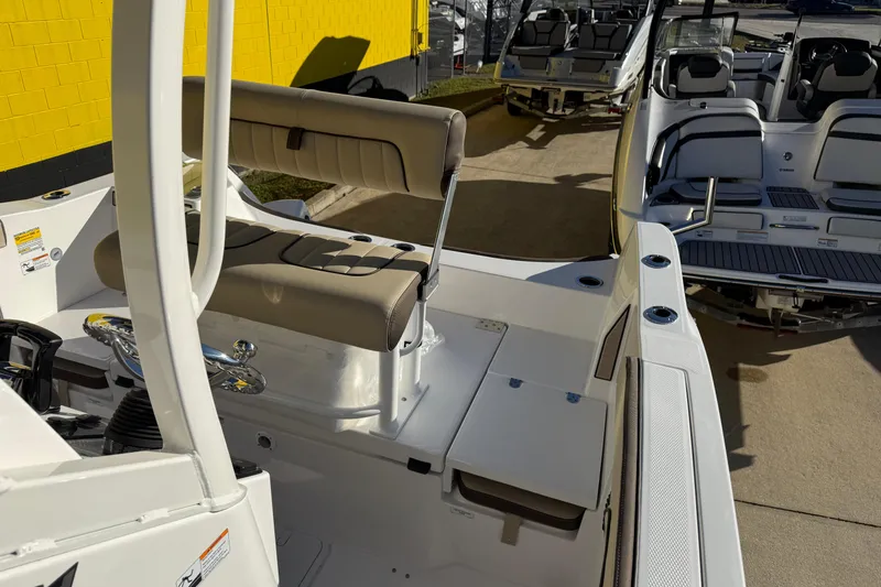 Slide: The Image of 2026 Yamaha Boats 222 FSH Sport E interior with seating and steering wheel, docked outdoors. - 35