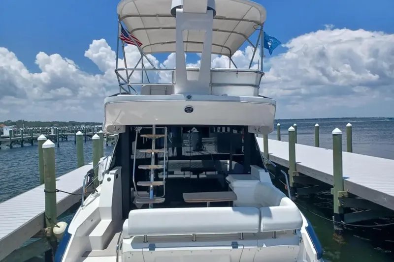 Slide: The Image of 2023 Regal 42 FXO yacht docked, showcasing spacious deck and elegant design under a clear sky. - 3