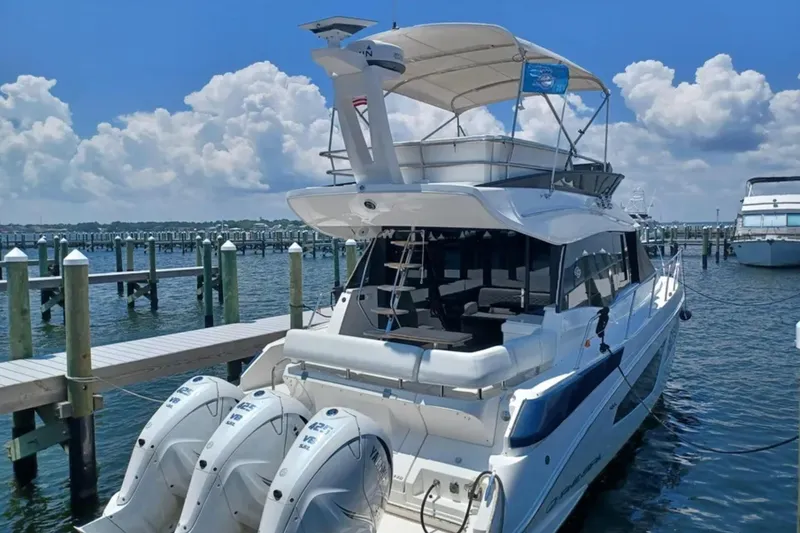 Slide: The Image of 2023 Regal 42 FXO yacht docked at marina with triple outboard engines. - 1