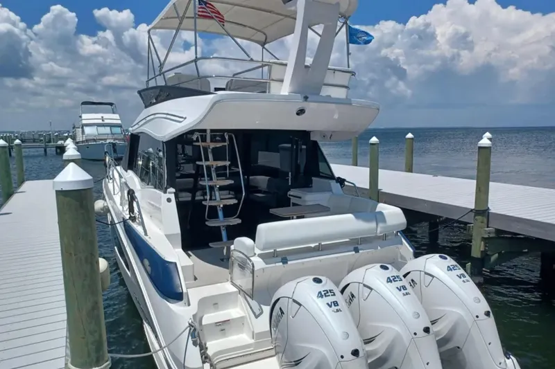 Slide: The Image of 2023 Regal 42 FXO yacht docked, featuring triple 425 V8 engines, under a partly cloudy sky. - 5