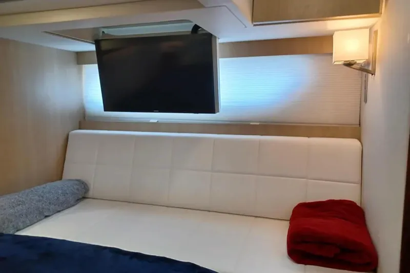 Slide: The Image of Luxurious interior of 2023 Regal 42 FXO yacht with TV, white seating, and red blanket. - 30
