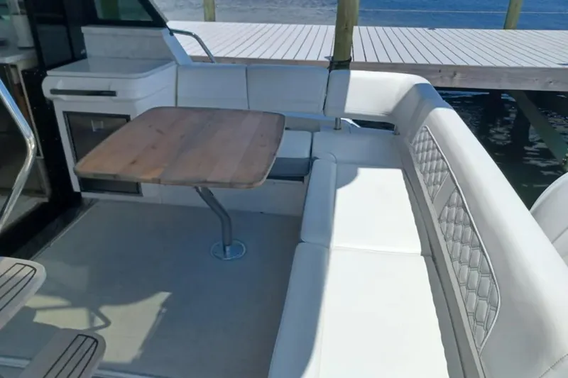 Slide: The Image of Luxurious seating area on 2023 Regal 42 FXO yacht with wooden table and white cushions. - 11