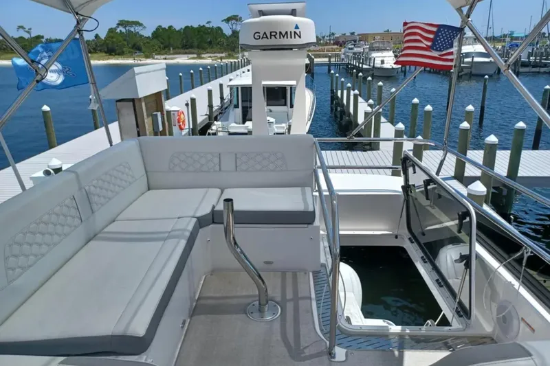 Slide: The Image of 2023 Regal 42 FXO yacht with seating area, docked at marina with American flag. - 14