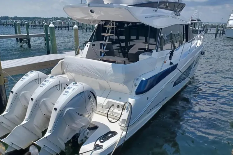 Slide: The Image of 2023 Regal 42 FXO luxury yacht docked with triple Yamaha outboard engines. - 2